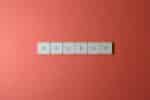 Free Close-up of keyboard keys spelling 'BACKUP' placed on a coral-colored surface. Stock Photo