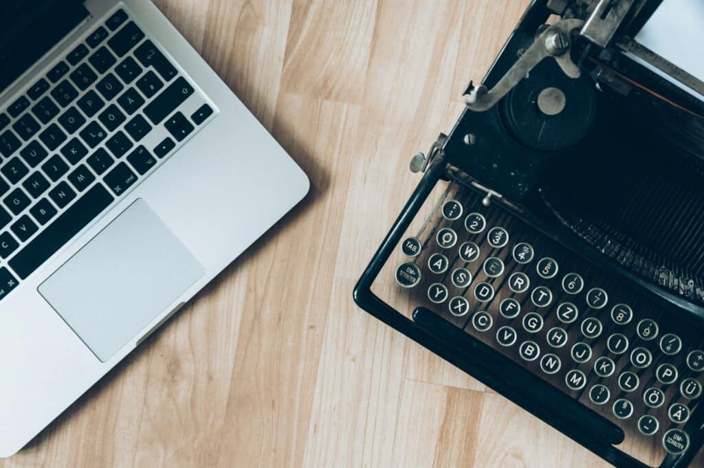 Modern laptop and vintage typewriter on desk.