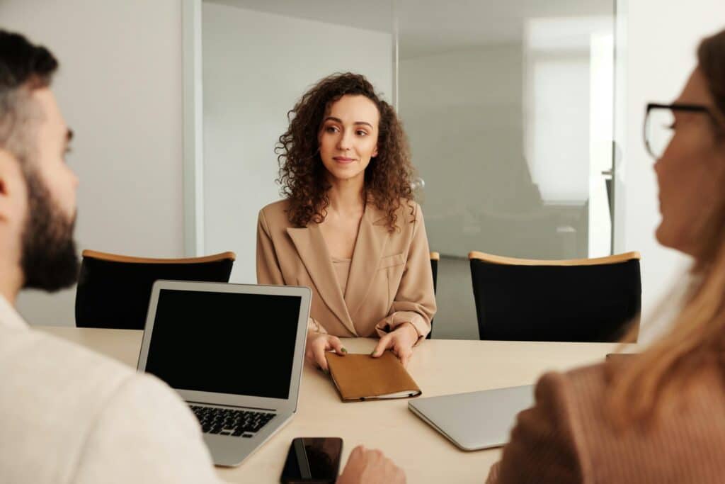 Professional woman in meeting with two colleagues.